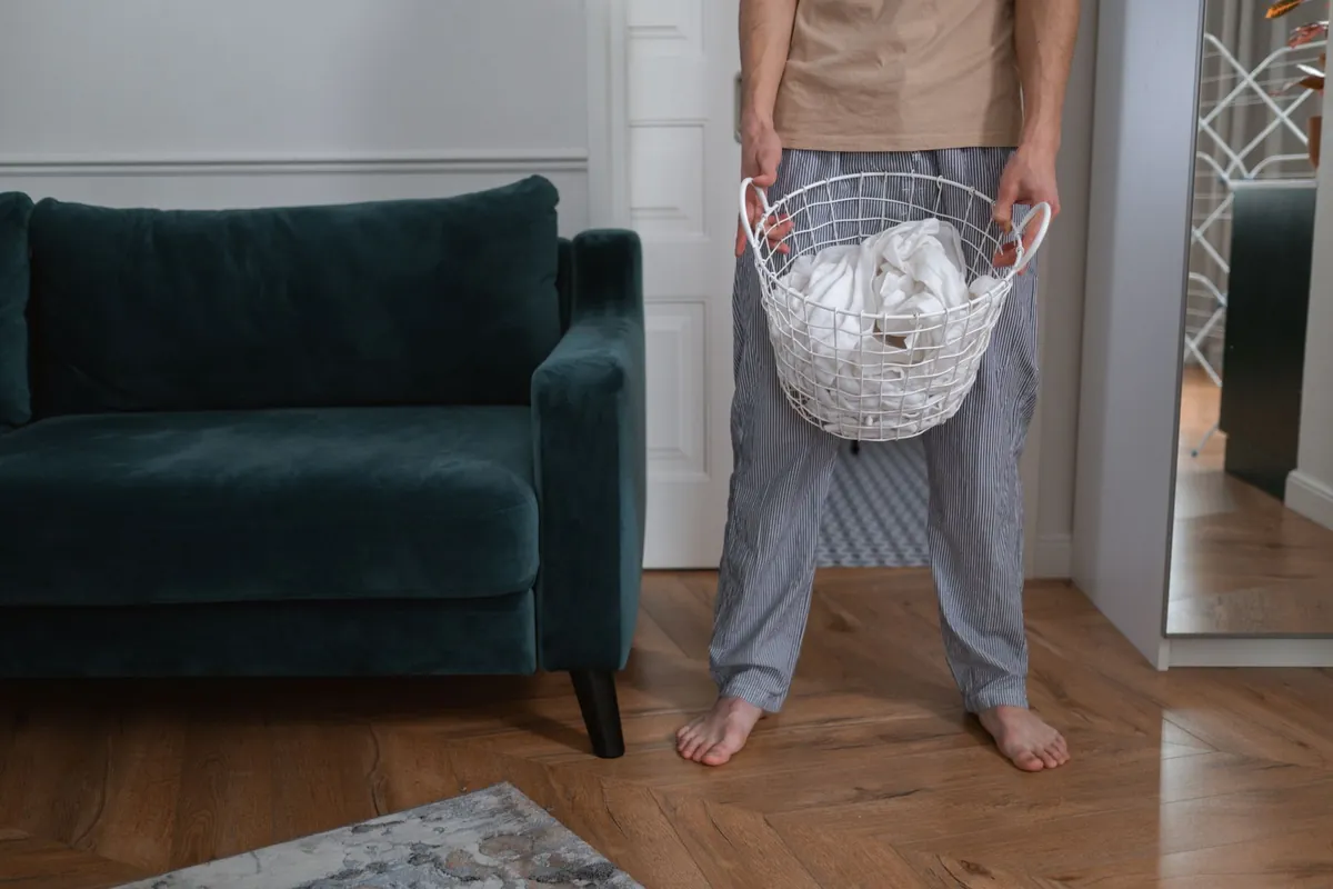 Persona con un canasto de ropa en su casa
